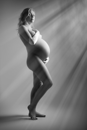 naked blond pregnant woman in sun rays monochromeの写真素材