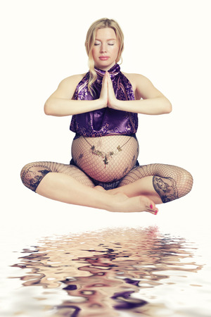 Pretty Blond Pregnant Woman Sitting in Yoga Pose Over her Reflectionの写真素材