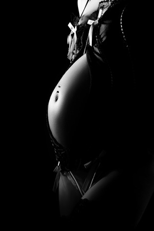stomach of pregnant woman in lingerie at dark monochromeの写真素材