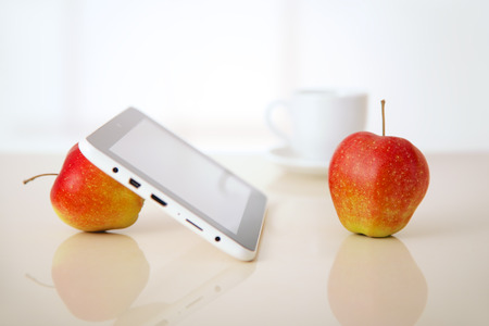 tablet pc with apple and coffee cup with reflections on tableの写真素材