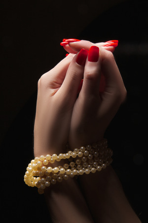 praying woman hands with necklace on black backgroundの写真素材