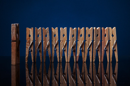 clothespin team in row with old leader on blue backgroundの写真素材