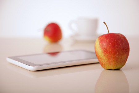 apples, tablet pc and coffee cup on tableの写真素材
