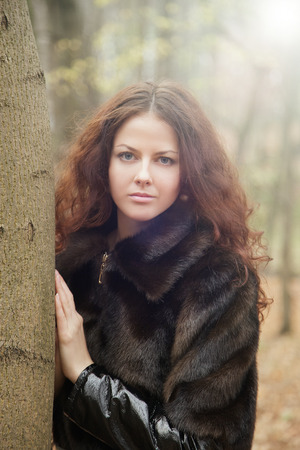 sad pensive girl in fur coat near tree の写真素材