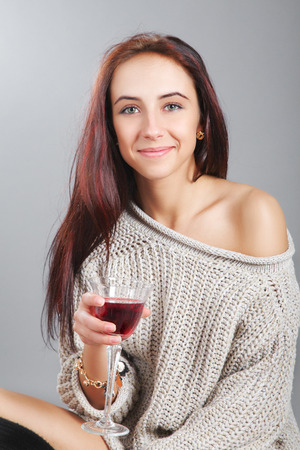 girl wearing in jamper sitting with wine on gray backgroundの写真素材
