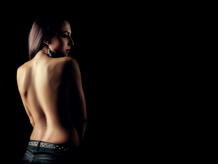 sad brunette woman bared back standing in dark