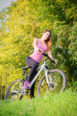 Young slim girl biking in evening parkの写真素材