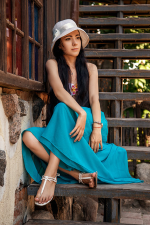 pretty pensive girl sitting on village staircasesの写真素材
