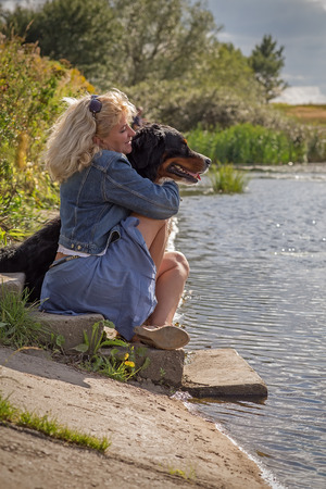 woman with her dog near summer pondの写真素材