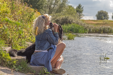 woman with her dog near summer pondの写真素材