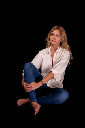 girl with ironic smile sitting on black backgroundの写真素材