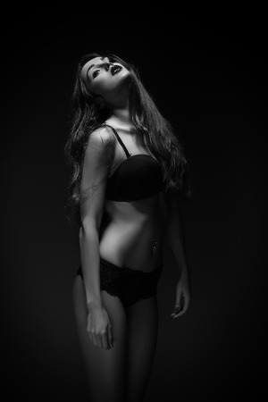 sad luxury girl in black lingerie on dark monochrome imageの写真素材