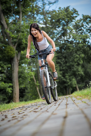 happy slim girl biking in summer parkの写真素材