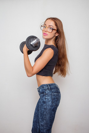 slim beautiful girl exercising with dumbbell on white backgroundの写真素材