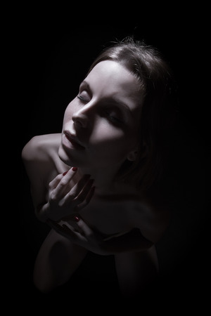 aroused woman on knees in darkの写真素材