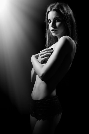 luxury young woman covering her body in dark low key monochrome imageの写真素材