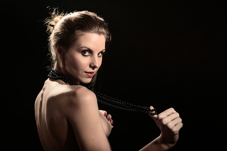 naked woman cover her breast on black backgroundの写真素材