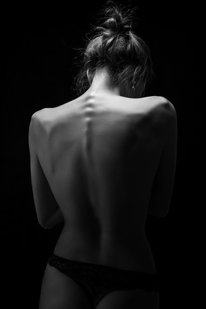 naked female tanned back on black background, monochromeの写真素材