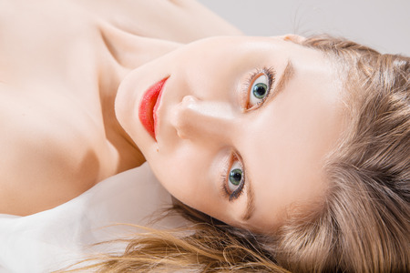 pretty naked woman lying on white bedの写真素材