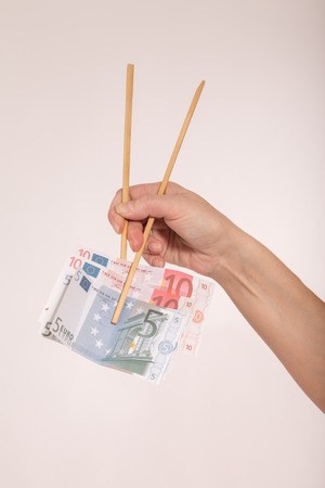 female hand with chopsticks and euro banknotesの写真素材