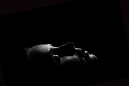 young female face profile with closed eyes in dark, monochromeの写真素材