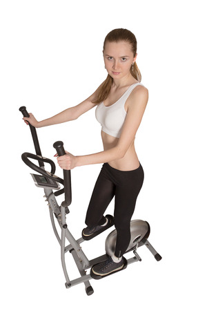 slim beautiful woman posing on home elliptical trainer isolatedの写真素材