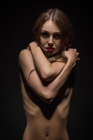 sad young woman covering her body in darkの写真素材