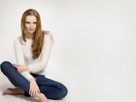 cute young woman sitting on white background with copyspaceの写真素材