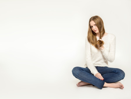 cute young woman sitting on white background with copyspaceの写真素材