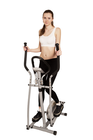 slim beautiful woman exercising on home elliptical trainer isolatedの写真素材