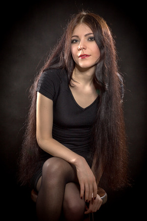 pretty woman with long hair sitting on black backgroundの写真素材