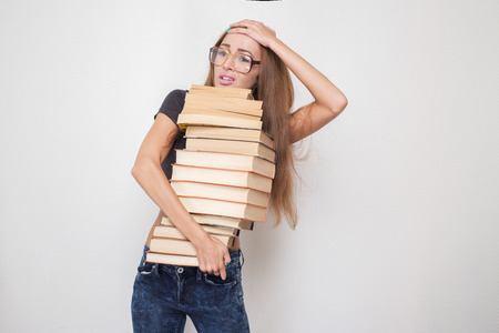 shocked girl with stacked books in hands isolated on white backgroundの写真素材