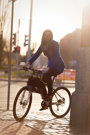 woman on bike in town under light raysの写真素材