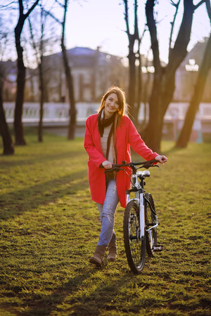 pretty girl with bike walks in parkの写真素材