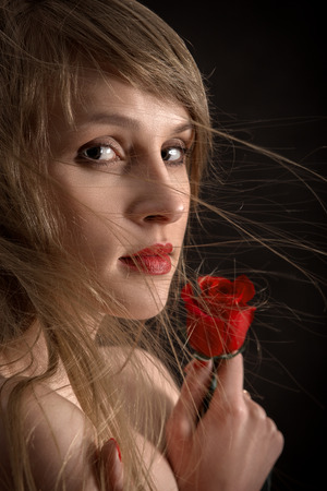 pretty girl with long hair and red rose on blackの写真素材