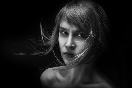 sad girl with flying hair in darkの写真素材