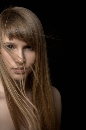serious young woman with long hair in darkの写真素材