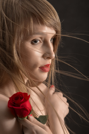 pretty girl with long hair and red rose on blackの写真素材