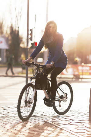 businesswoman on bike in town under light raysの写真素材