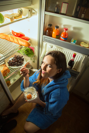 woman eating dessert near refrigeratorの写真素材