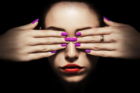 young woman with covered eyes on black backgroundの写真素材
