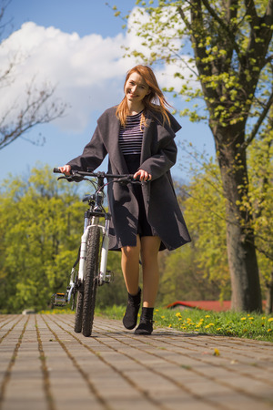 pretty girl with bike in spring parkの写真素材