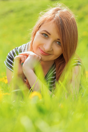 happy red hair girl lying on grassの写真素材