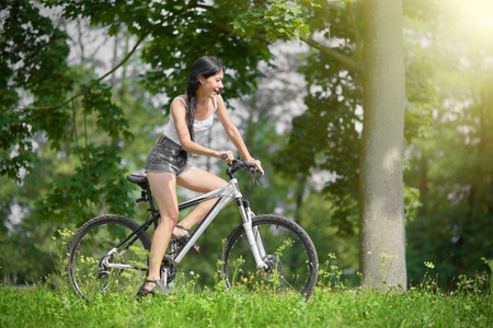happy slim girl biking in summer parkの写真素材