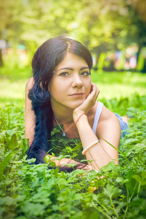 sad girl lying on green grassの写真素材