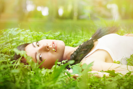 sad girl lying on green grassの写真素材