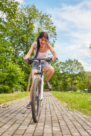 happy girl driving on bicycle on cobblestone in parkの写真素材