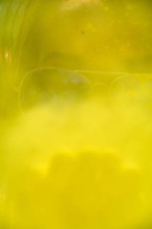 woman blowing yellow Holi Powder at camera blurred background with copyspaceの写真素材