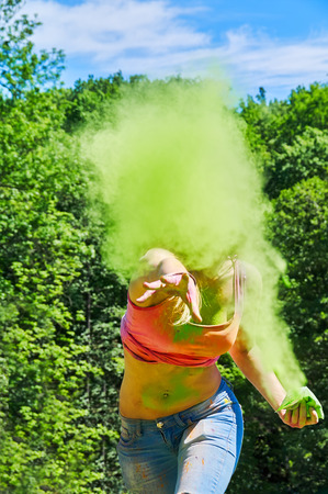 woman throwing green holi powder at cameraの写真素材