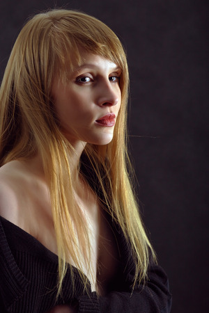 serious young woman with long hair in darkの写真素材